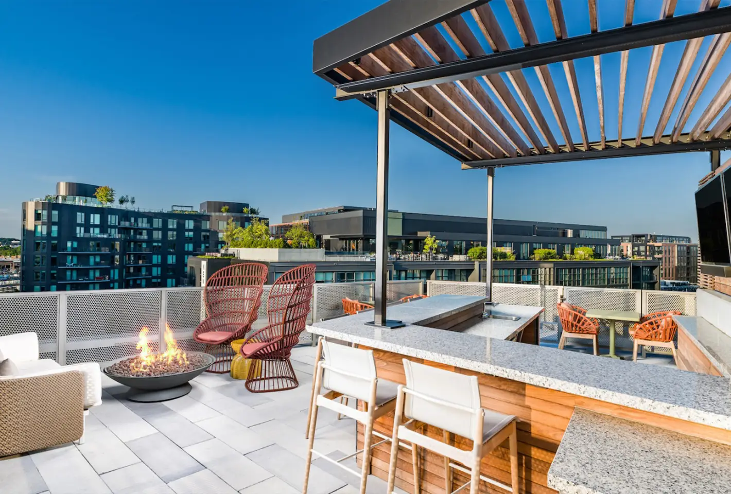 Outdoor rooftop lounge with stylish bar seating, fire pits, and spectacular city views