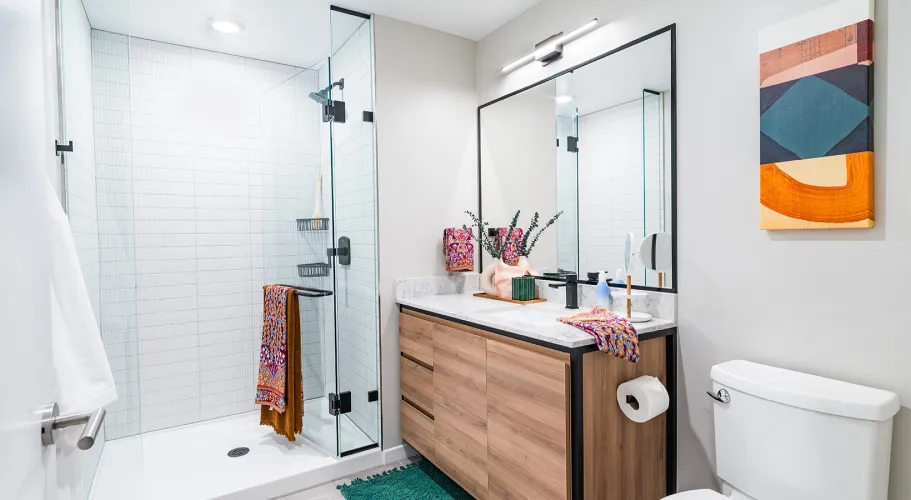 Elegant bathroom featuring a sleek glass shower, unique decor, and warm wood vanity