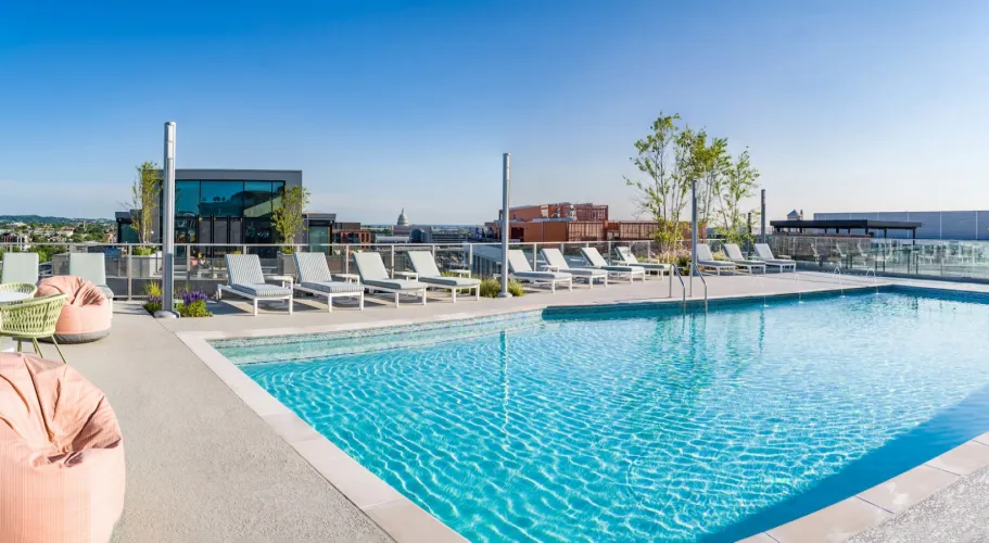 Rooftop pool area with serene water, relaxing loungers, and expansive city backdrop
