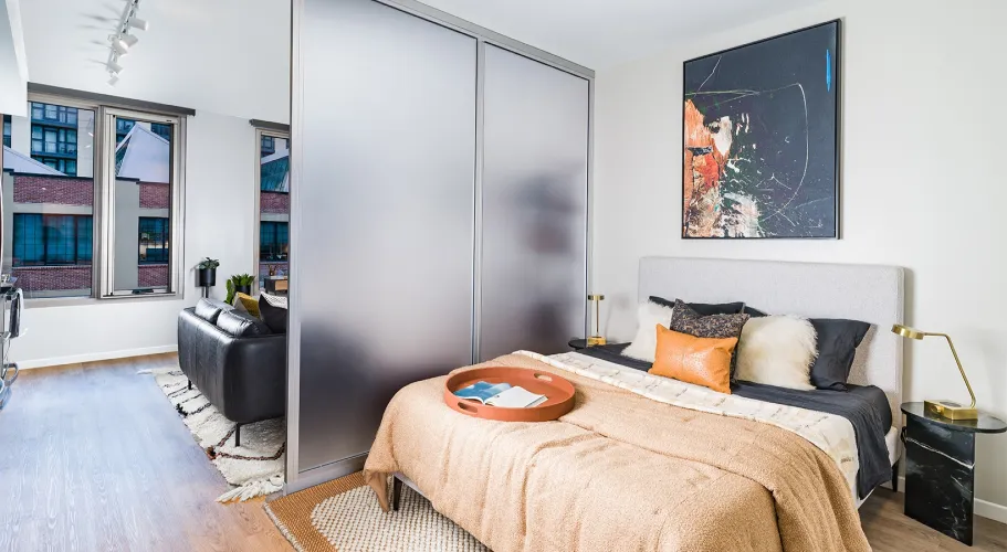 Bright bedroom space with modern furnishings, abstract art, and frosted sliding partitions