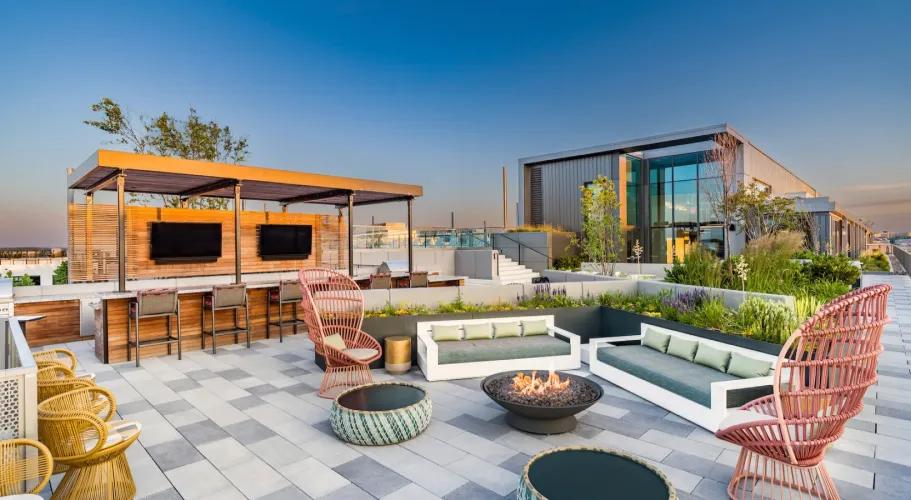 Rooftop bar with stylish seating, fire pit, and sweeping views of the city at sunset