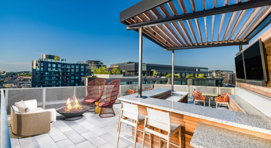 Modern rooftop area with firepit seating and expansive views of a vibrant urban landscape