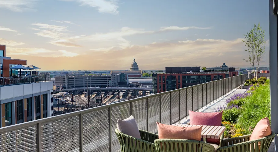Scenic rooftop terrace view featuring Capitol dome, stylish seating, and lush greenery at sunset