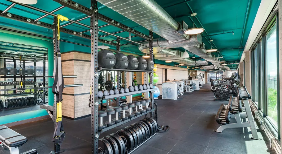Fully-equipped workout area with organized weights, cardio machines, and an industrial-chic design