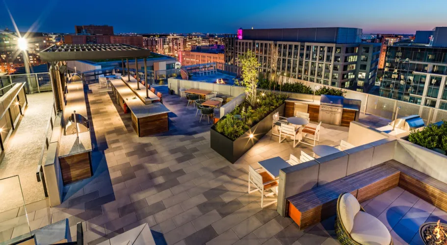 Rooftop patio illuminated at dusk with stylish seating, plants, and breathtaking cityscape views