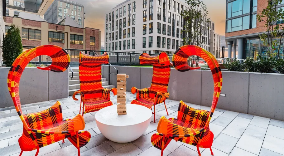 Bright courtyard with vibrant red-orange chairs and a central table for a stylish outdoor retreat