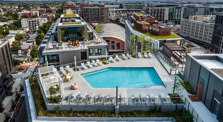 Rooftop pool surrounded by sun loungers and scenic views of a bustling city skyline
