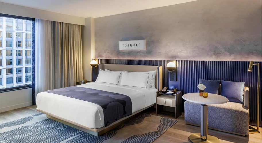 Chic hotel room with a king-size bed, abstract wall art, and cozy seating