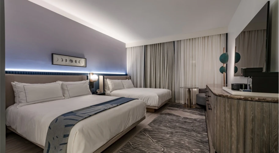 Contemporary hotel bedroom with two plush beds and soft ambient lighting
