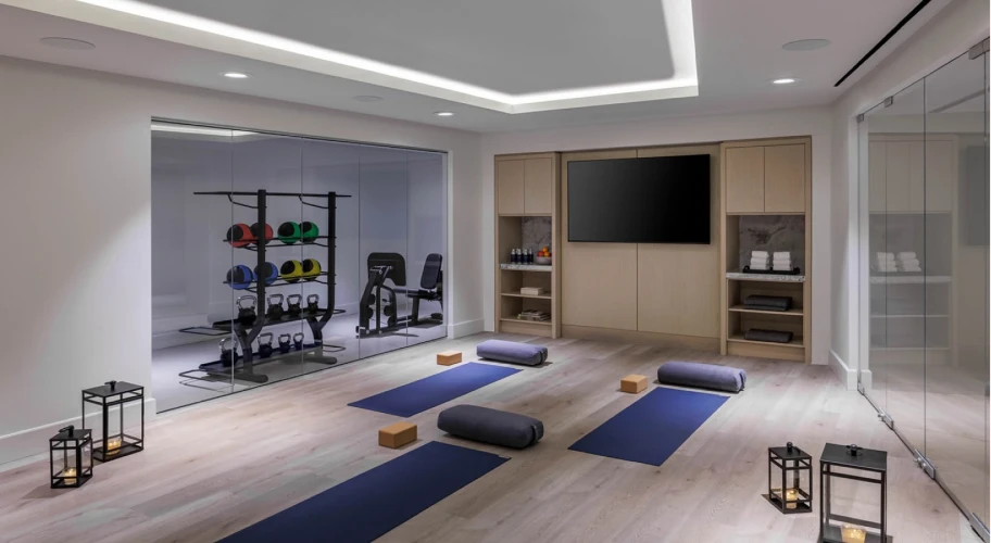 Modern gym area featuring yoga mats, dumbbells, and sleek wooden decor
