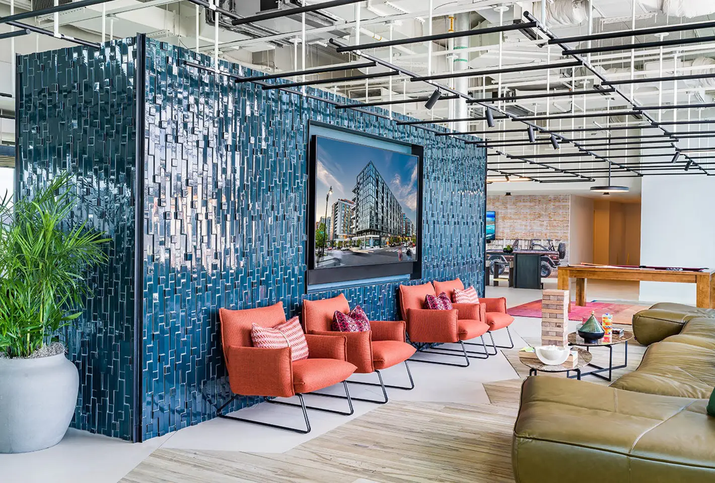 Contemporary lounge with sleek design, plush red chairs, and a mosaic tile wall featuring a screen