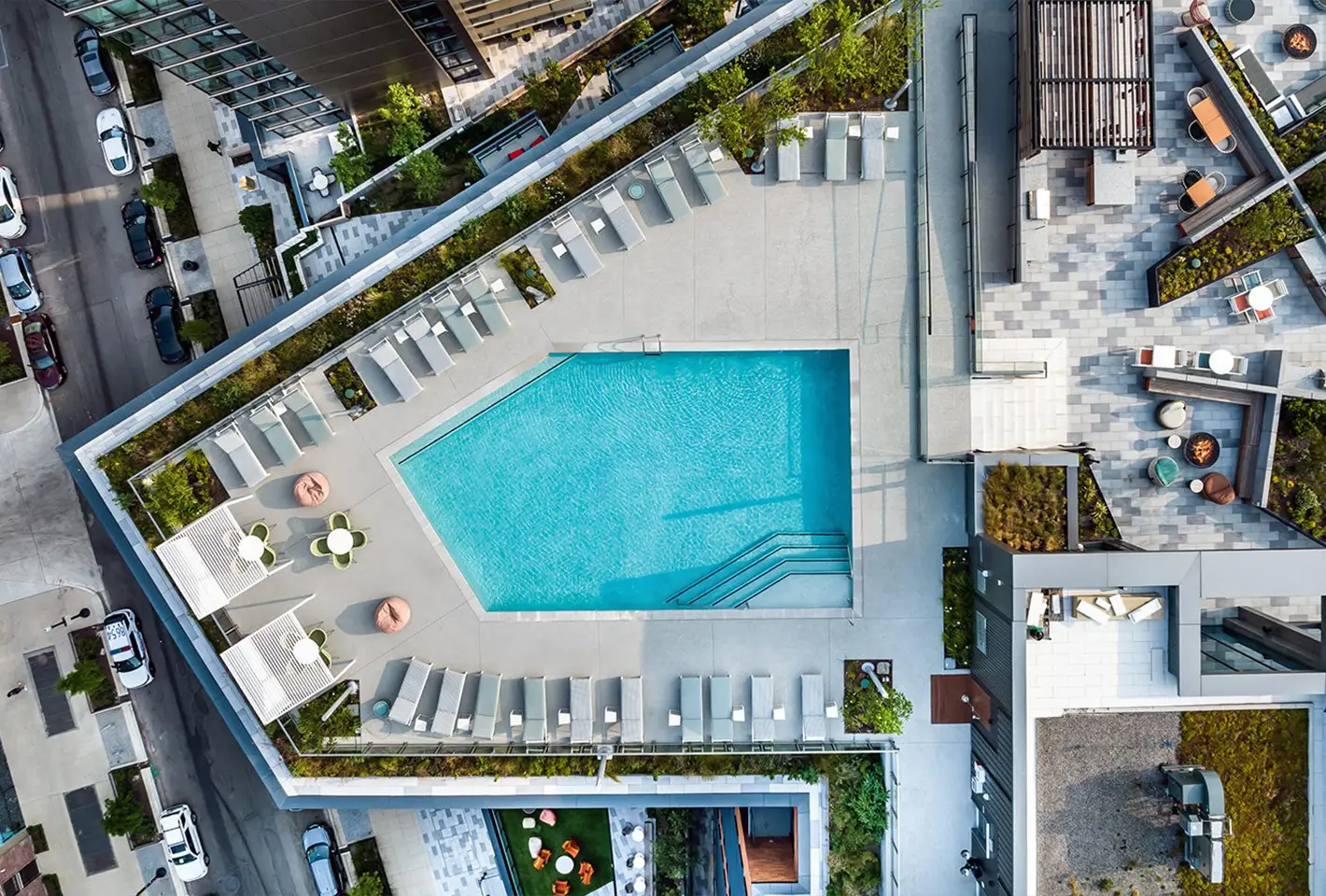 Overhead view of rooftop pool area with lounge seating and greenery