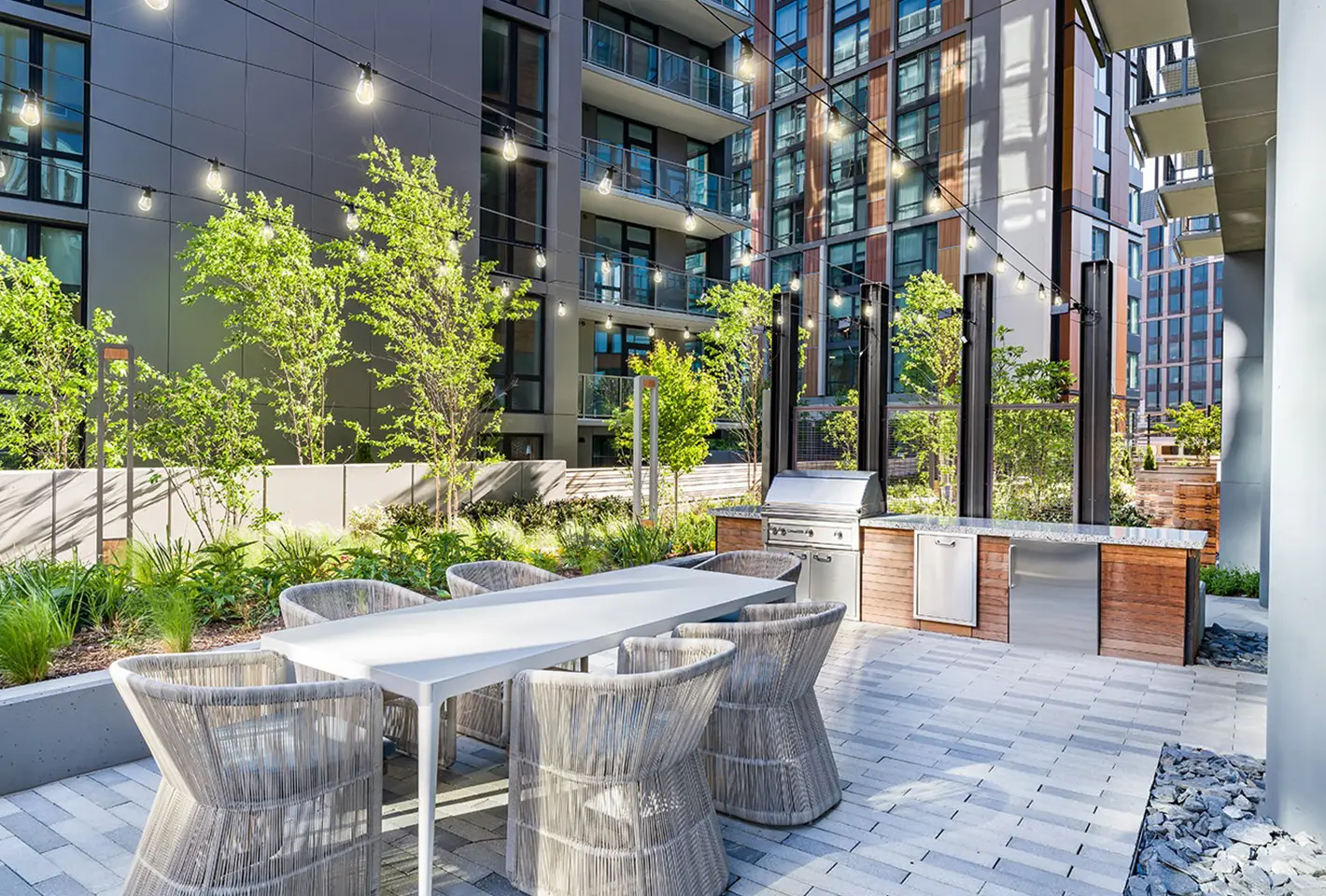 Stylish rooftop setting with a grill station, elegant tables, and vibrant landscaped surroundings