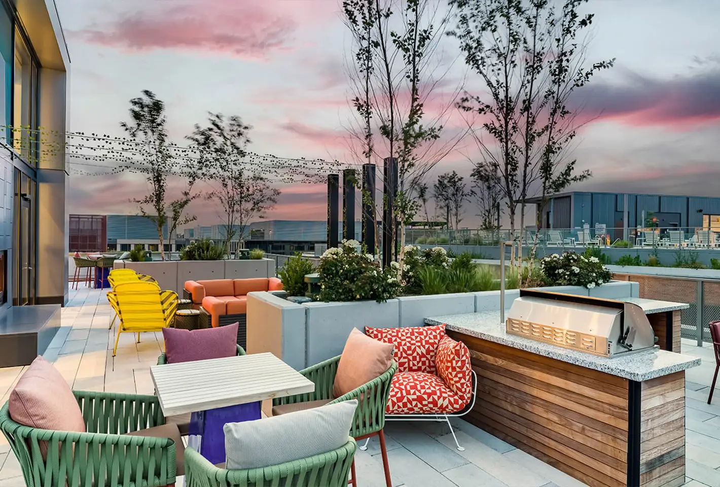 Vibrant rooftop lounge with colorful seating and decorative greenery at sunset