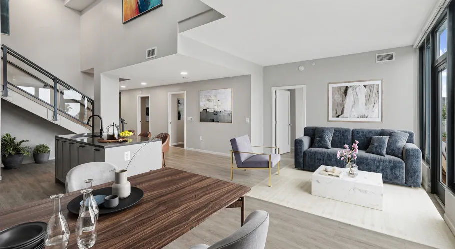 Spacious modern living room with gray couch, sleek decor, and floor-to-ceiling windows