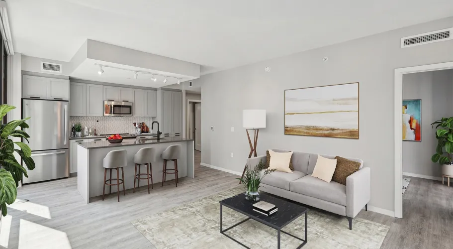 Open-concept apartment with gray couch, modern kitchen, and minimalist design elements