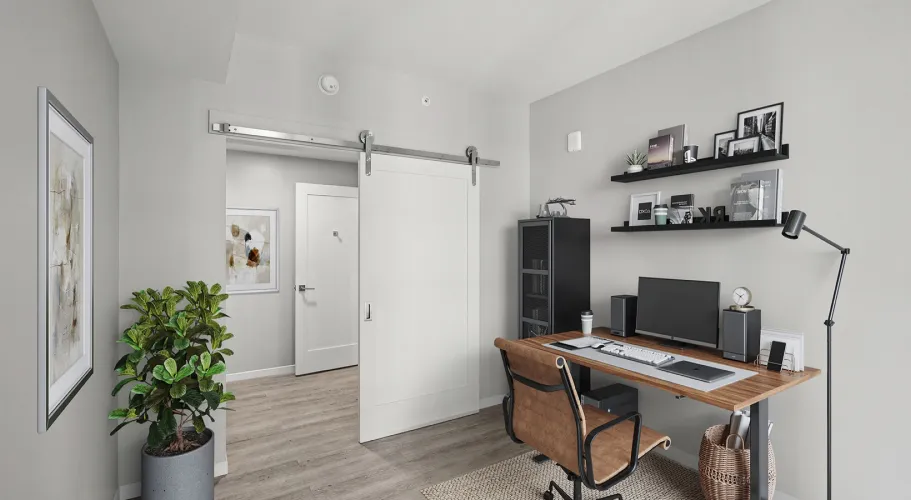Compact home office with wooden desk, shelves, and sliding barn door in minimalist decor
