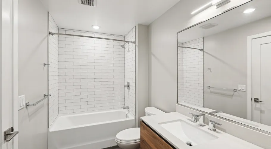 Modern bathroom with subway-tile shower, sleek white vanity, and large framed mirror