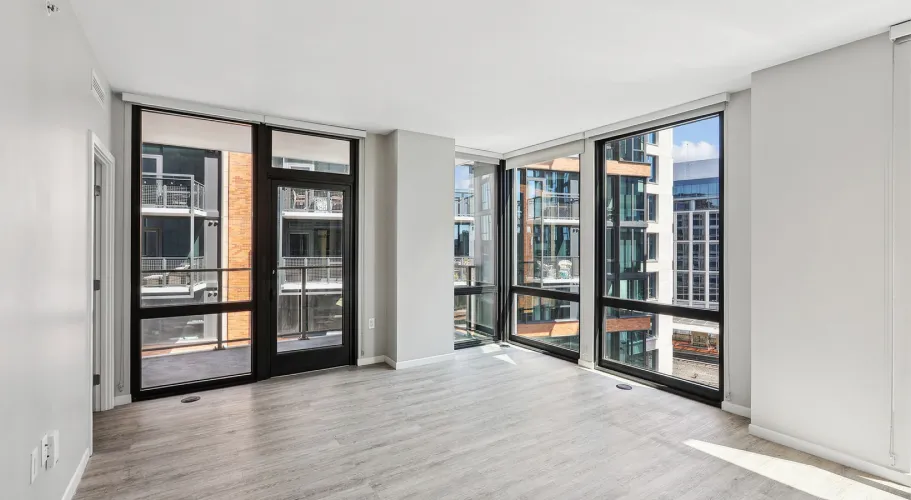 Empty modern apartment with large windows and light wood flooring