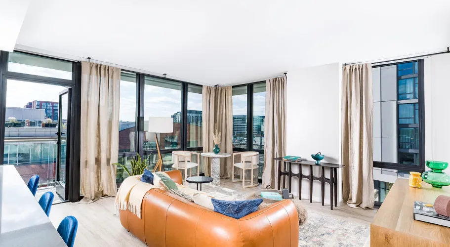 Bright and airy living room with large windows, modern furniture, and cityscape views