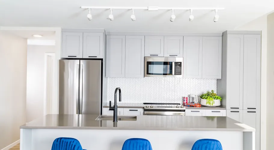 Open-concept kitchen with stainless steel appliances and bold blue barstools at the counter