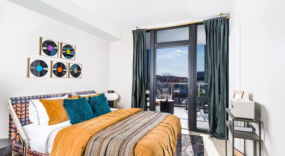Elegant bedroom with vibrant orange bedding, dark curtains, and access to a private balcony