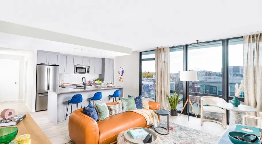 Open living area with a modern kitchen, leather sofa, and floor-to-ceiling windows for natural light