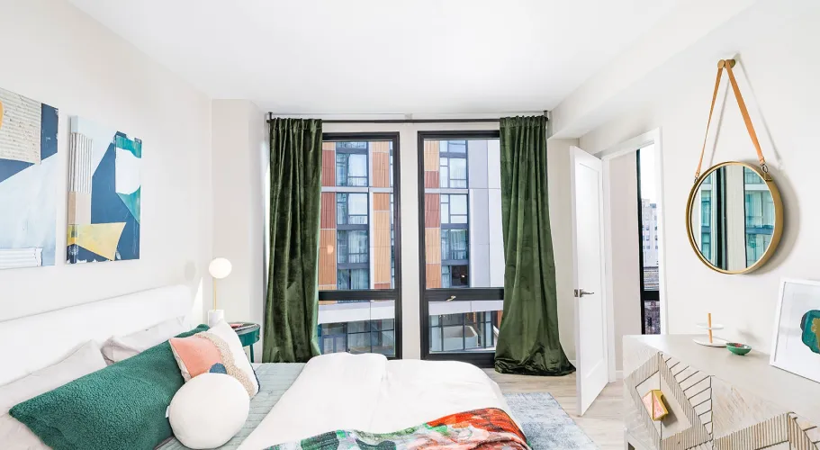 Contemporary bedroom featuring artistic wall decor, dark green curtains, and floor-to-ceiling windows