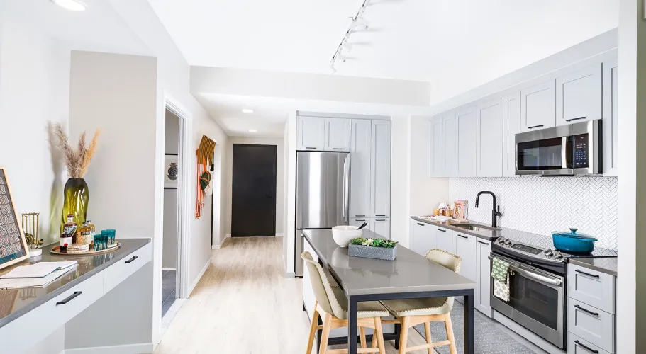 Open-concept kitchen with sleek gray cabinetry, modern appliances, and an elegant dining island