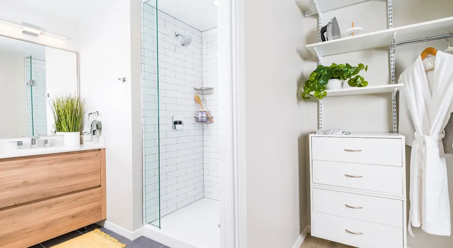 Modern bathroom with subway-tiled shower, wooden vanity, and open shelving for storage