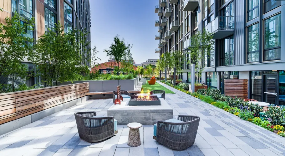 Outdoor courtyard with a fire pit, modern seating, and lush landscaping in an urban setting.