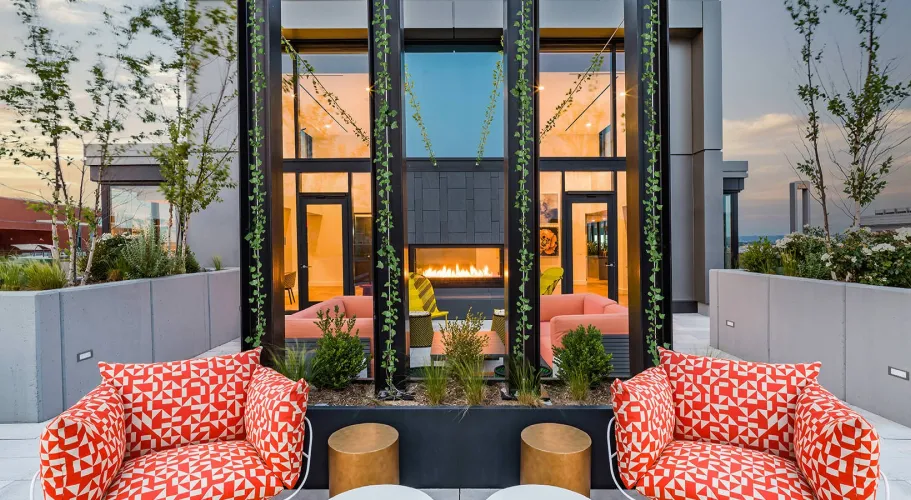Chic rooftop lounge with bold patterned seating and modern fireplace surrounded by lush greenery
