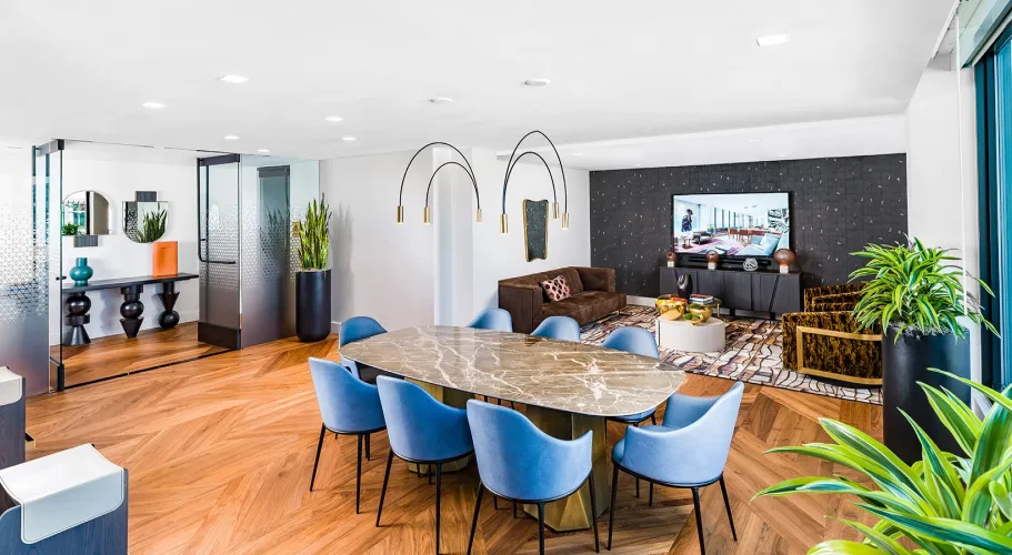 Sophisticated dining room with marble table, bright blue chairs, and open seating area nearby