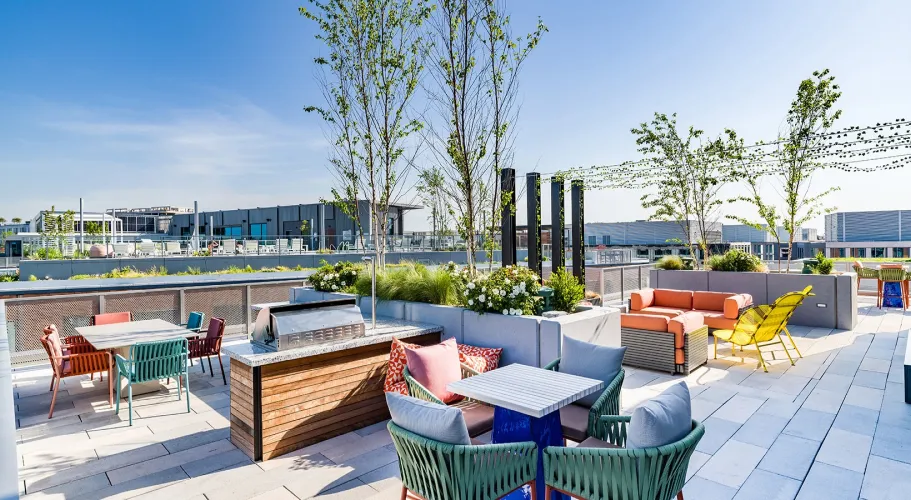 Rooftop terrace with colorful seating, modern dining setup, and vibrant landscaping under a clear sky