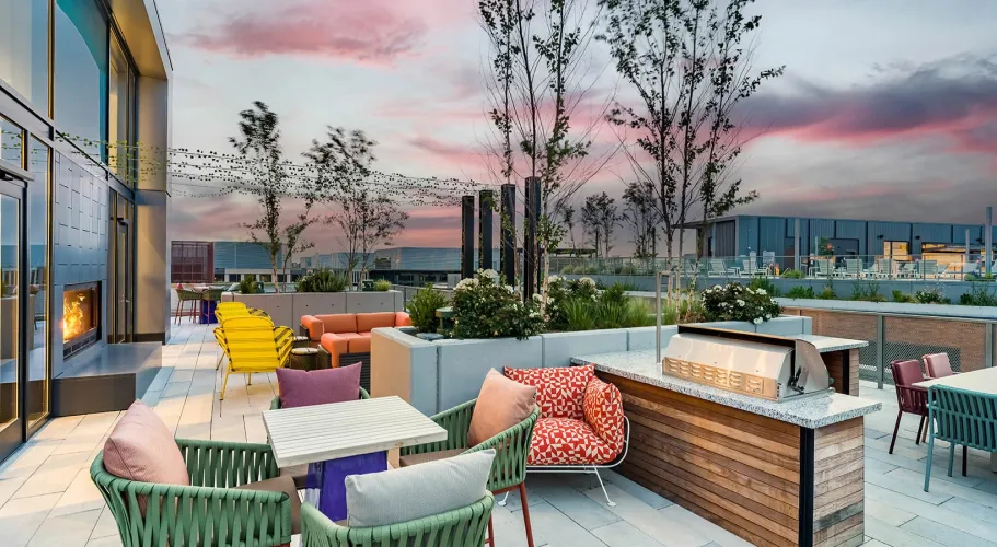 Elegant rooftop lounge with modern decor, lush greenery, and a picturesque evening sky