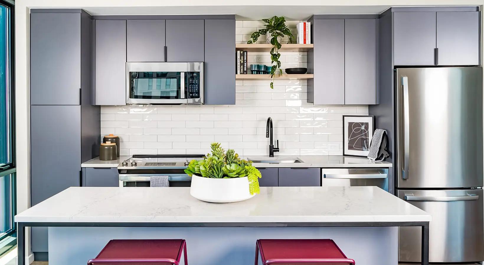 Modern kitchen with sleek gray cabinets, quartz countertop, and stainless steel appliances