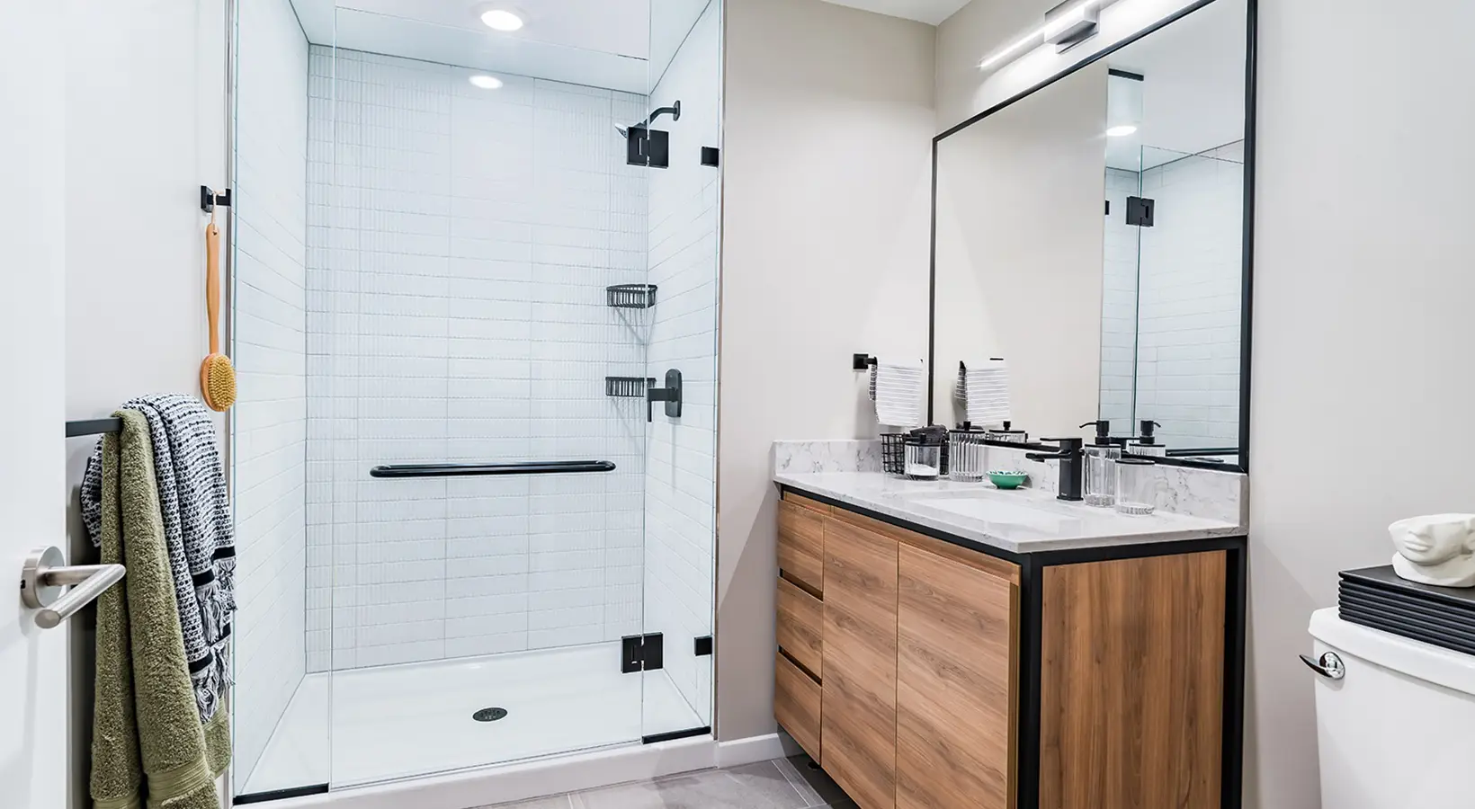 Elegant bathroom with glass shower enclosure, wood vanity, and black fixtures