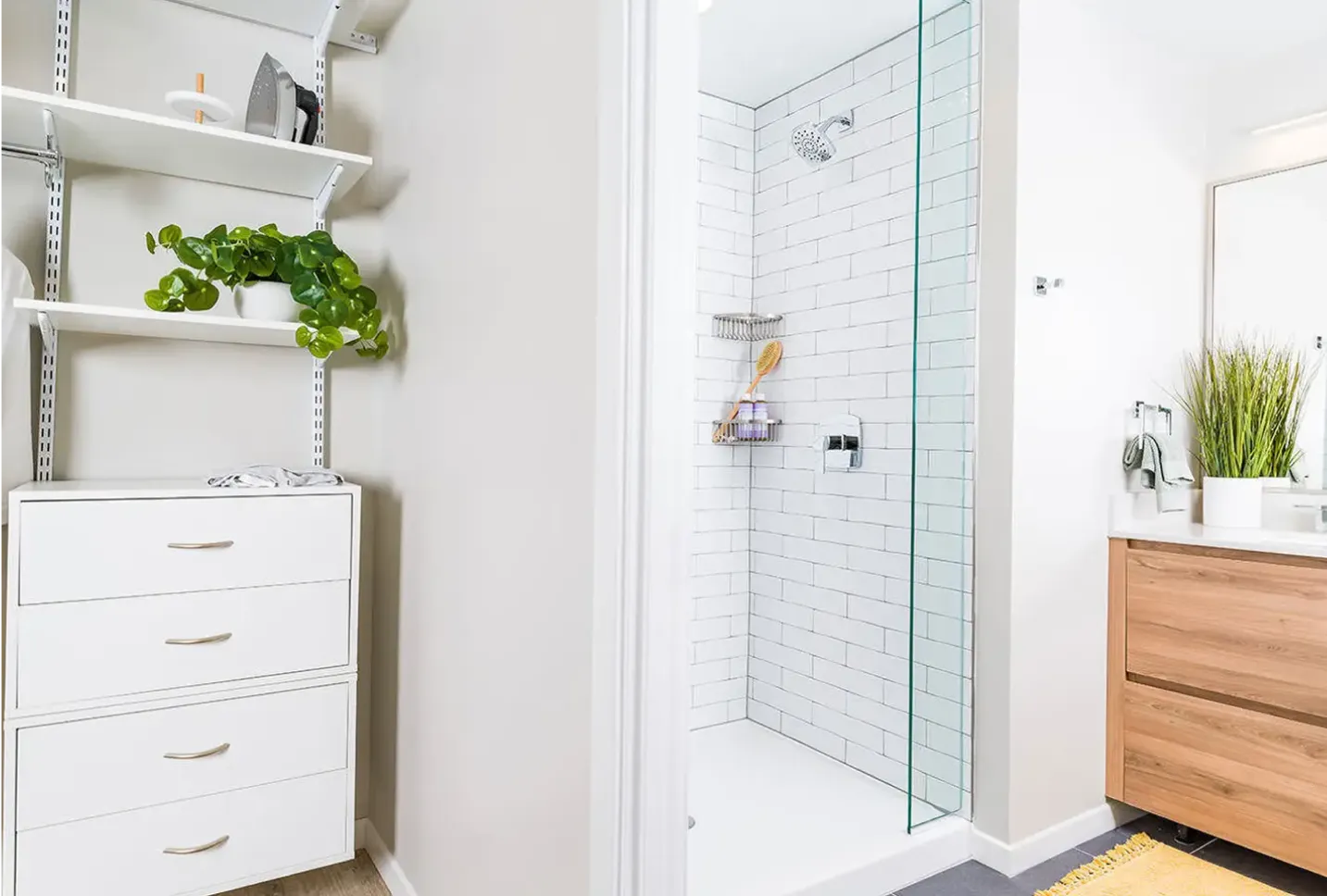 Modern bathroom with glass shower, white shelving, and minimalist decor
