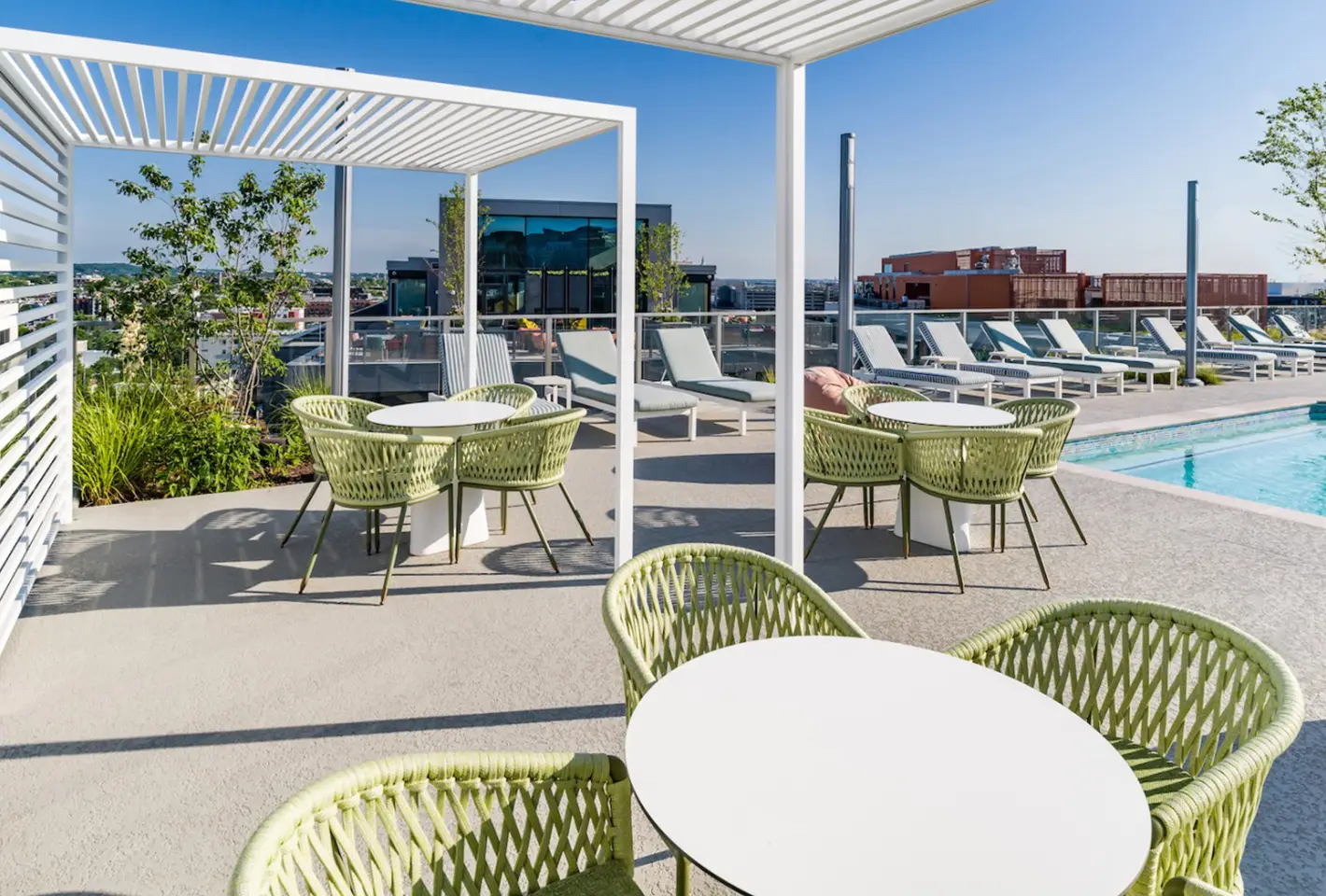 Rooftop terrace with cozy seating areas, pool, and panoramic views of the city skyline