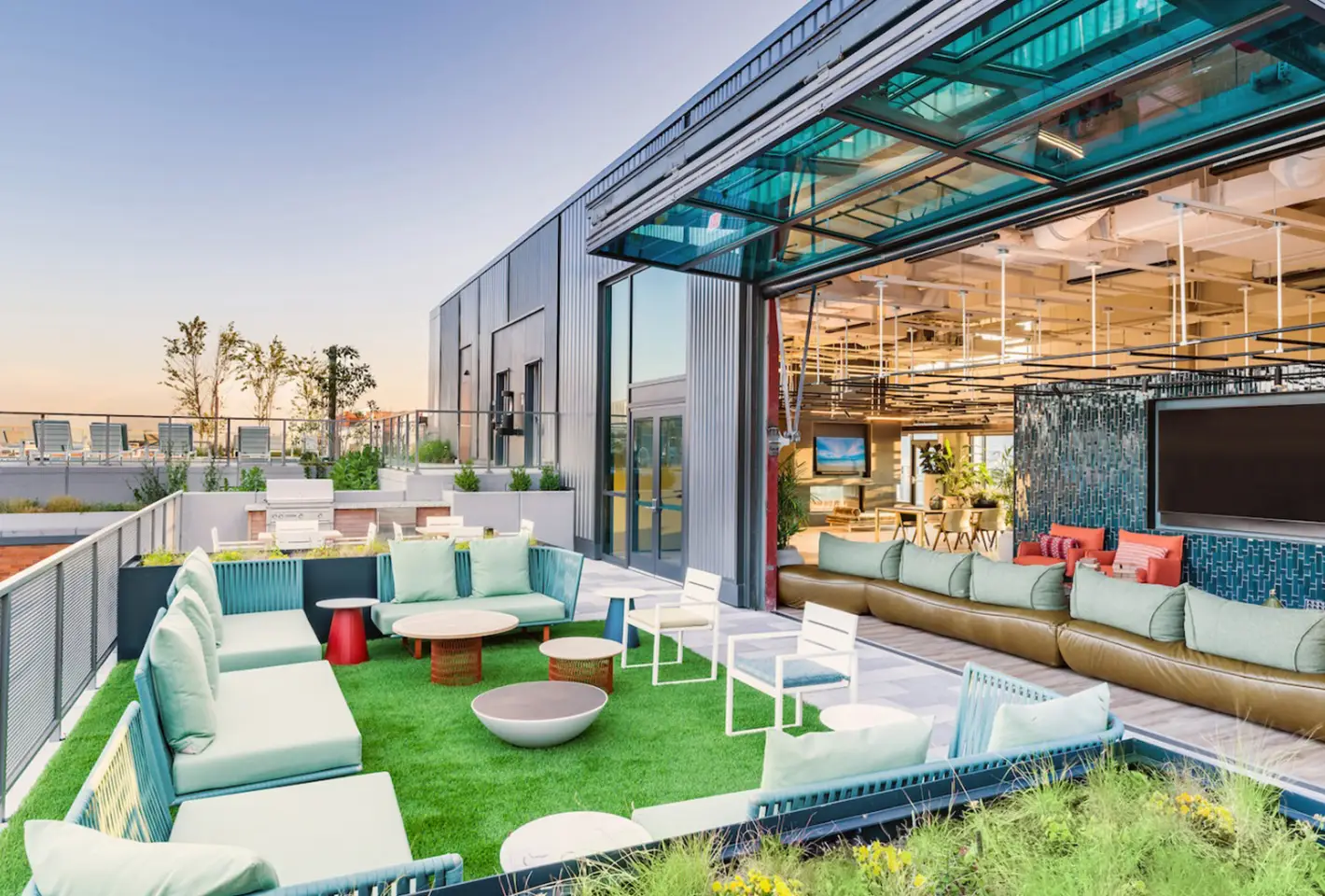 Chic outdoor lounge featuring lush grass seating areas and retractable glass partitions