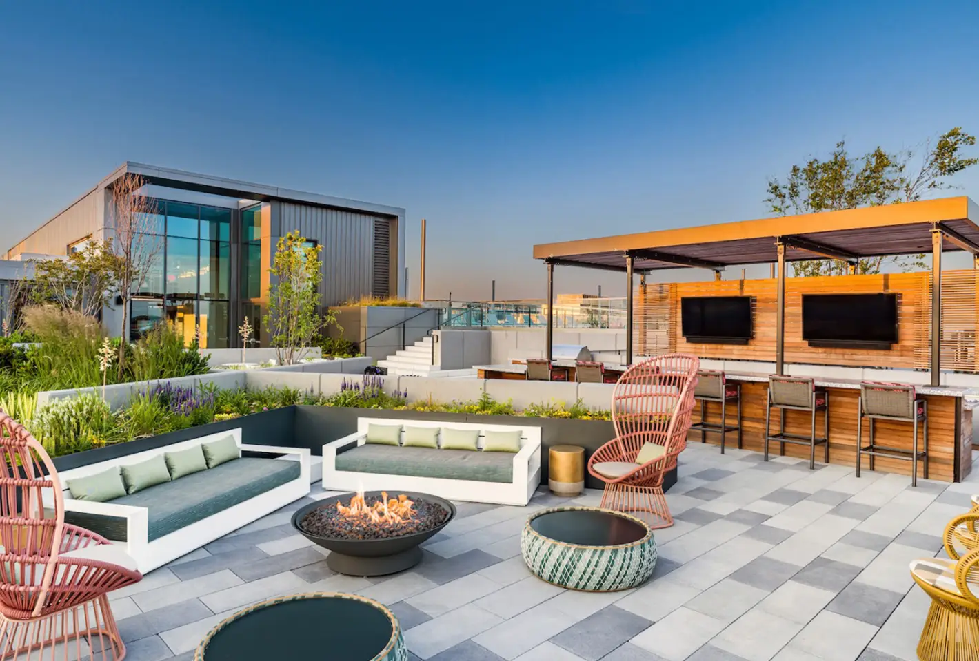 Lively rooftop bar area with wooden accents, multiple screens, and comfortable seating