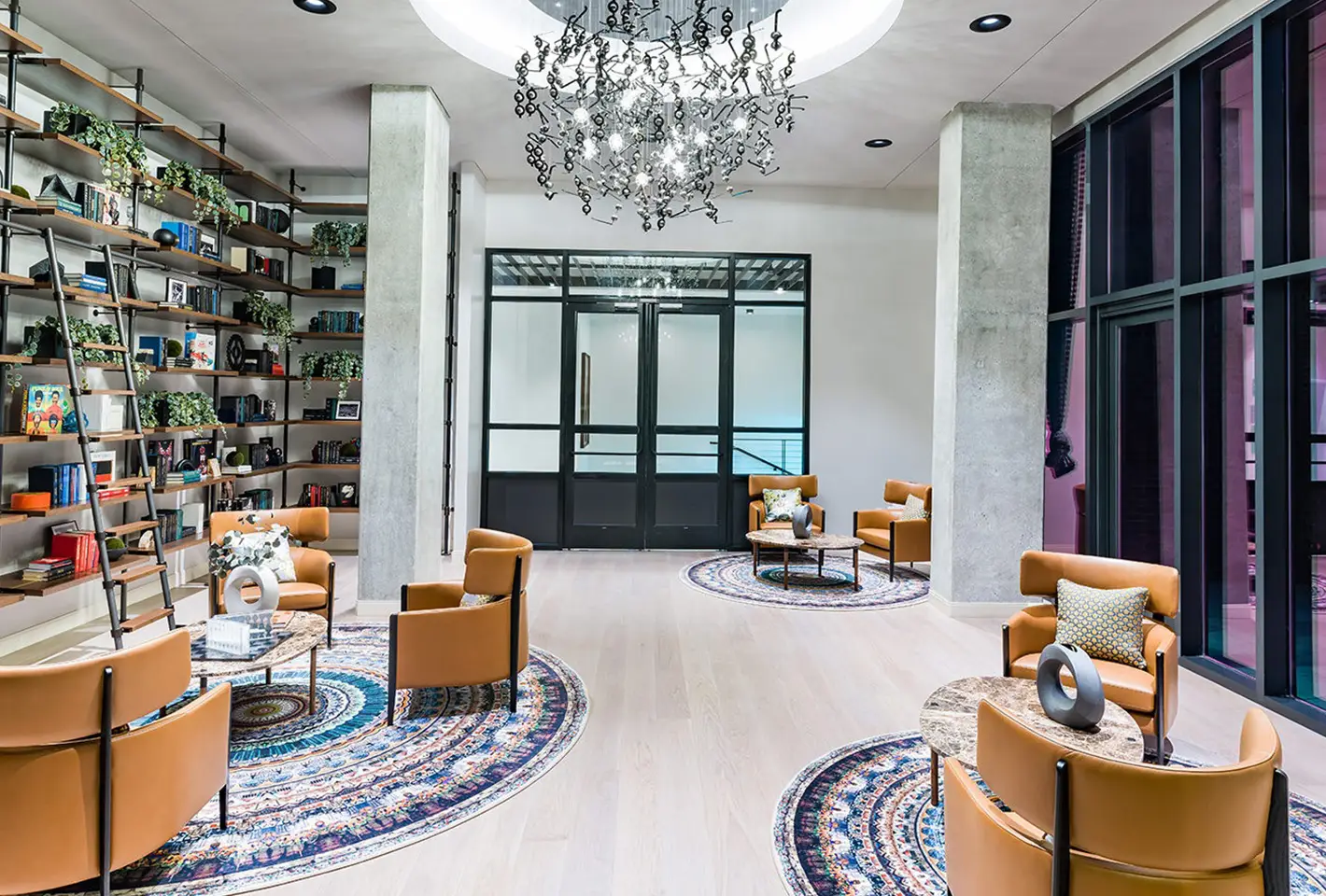 Luxury library lounge with leather chairs, artistic chandelier, and vibrant bookshelves