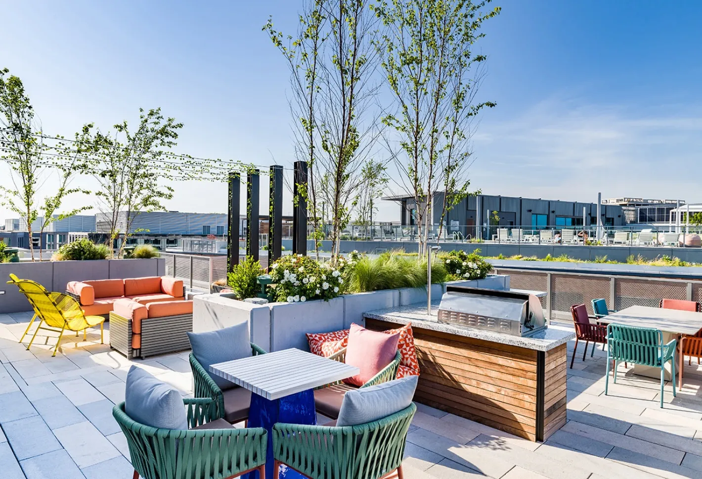 Vibrant rooftop lounge with colorful seating and lush greenery under a clear sky