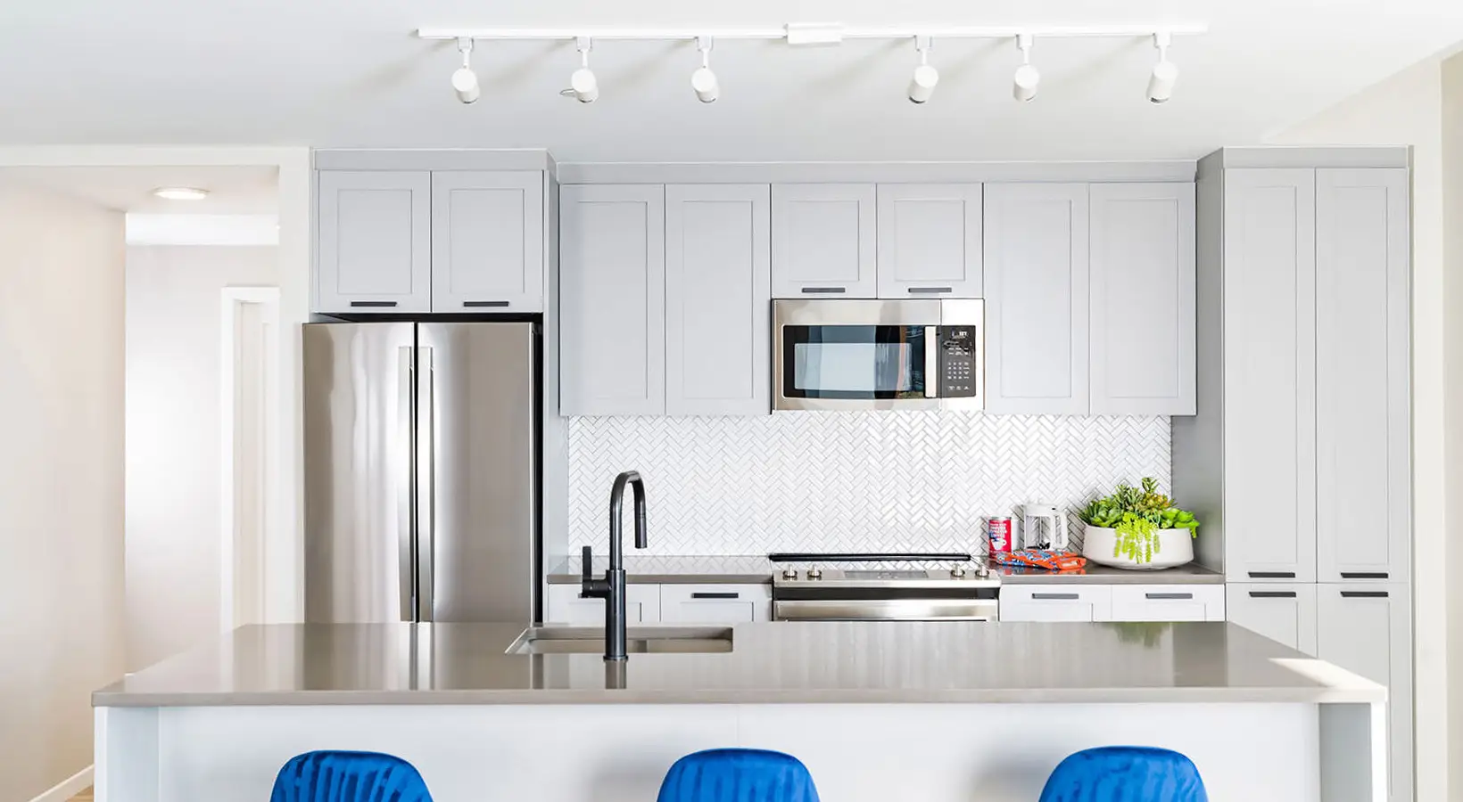 Contemporary kitchen design featuring a stylish island and white herringbone backsplash