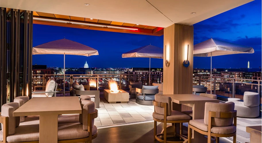 Upscale rooftop retreat with comfortable outdoor sofas, fire pits, and stunning city skyline views