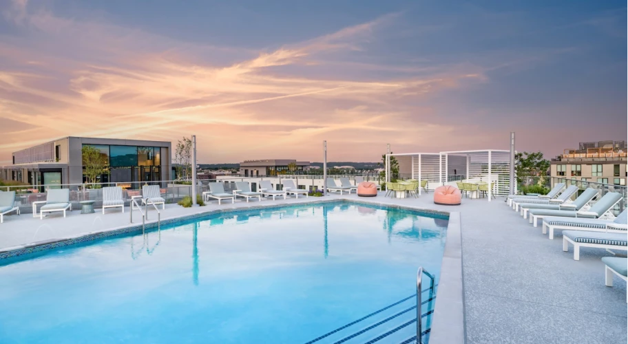 Serene evening rooftop pool reflecting a pastel sunset, surrounded by stylish seating